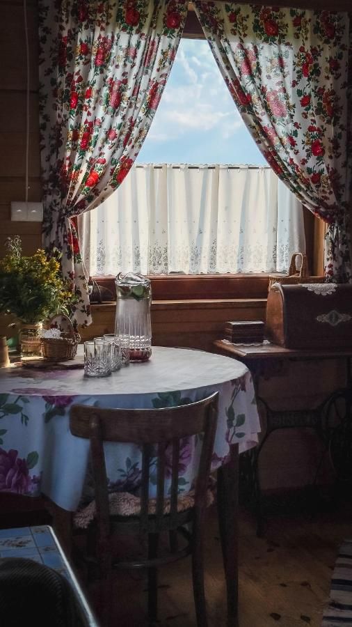 Stół z kwiecistym obrusem przy oknie z zasłonami w czerwone róże