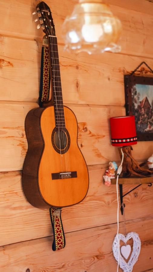 Gitara oparta o drewnianą ścianę obok czerwonej lampki